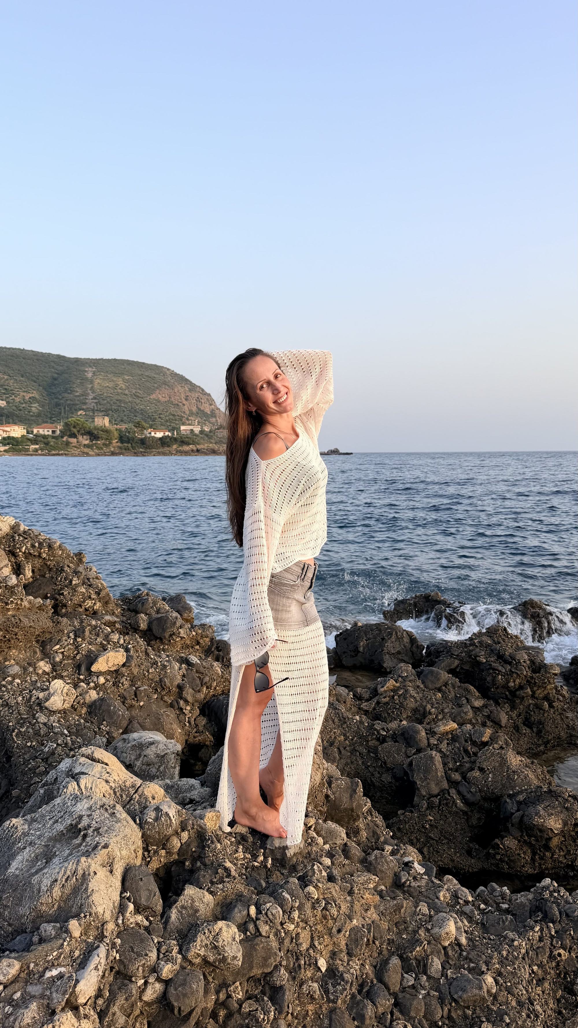 A woman in a hand-knit top watching the sunset over the sea