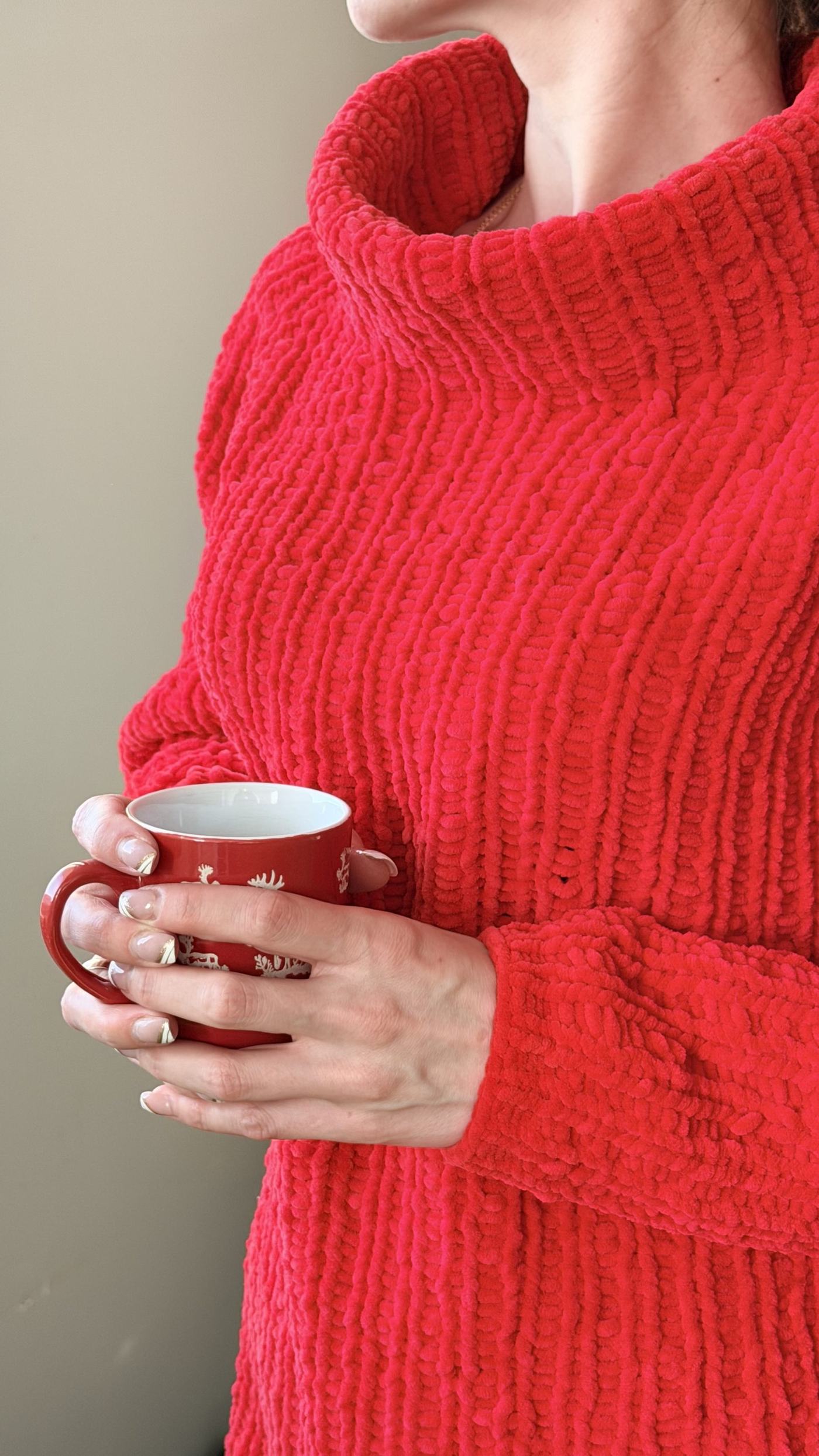 A cup of coffee held in hand-knit sleeves