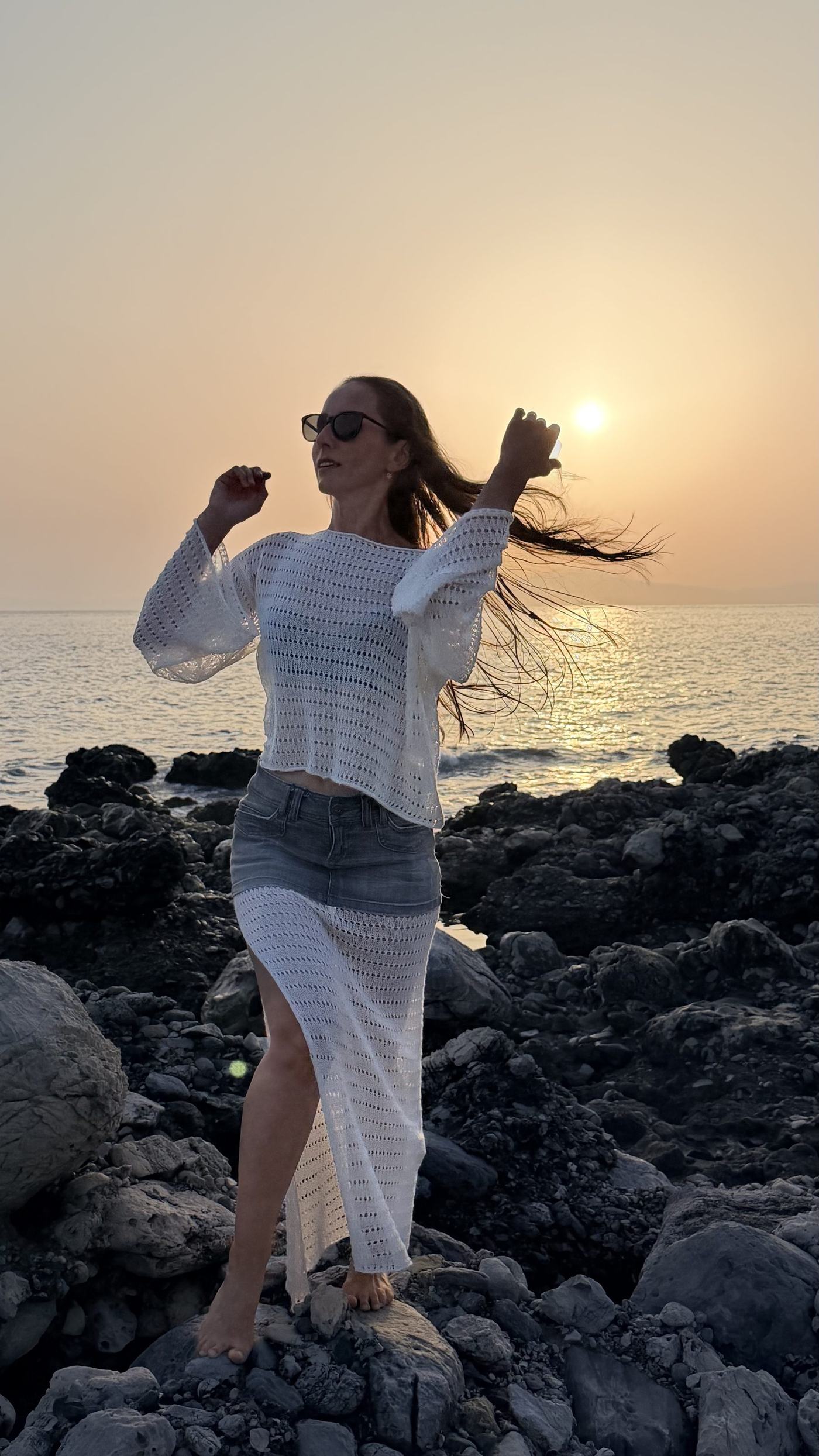 Golden hour by the sea, wearing a hand-knit piece
